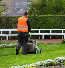 Gärtner beim rasenmähen mit Gehörschutz
